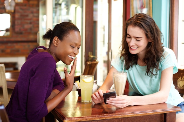 Zwei junge Frauen, die Handy Café betrachten