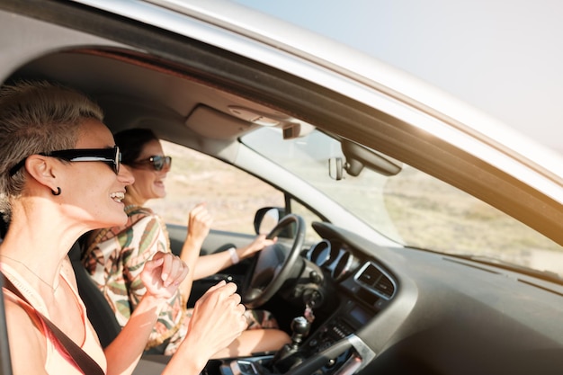 Zwei junge Frauen im Auto, die gemeinsam Musik hören und singen Konzept-Lifestyle-Spaß gemeinsam