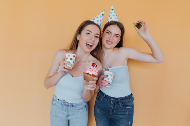 Zwei junge Frauen in Geburtstagshüten feiern Geburtstag