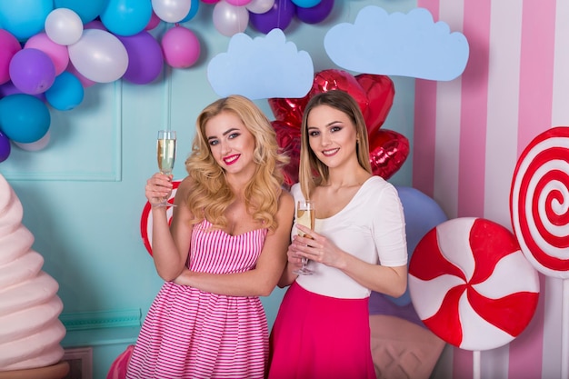 Foto zwei junge frauen in rosa kleidern halten gläser champagner