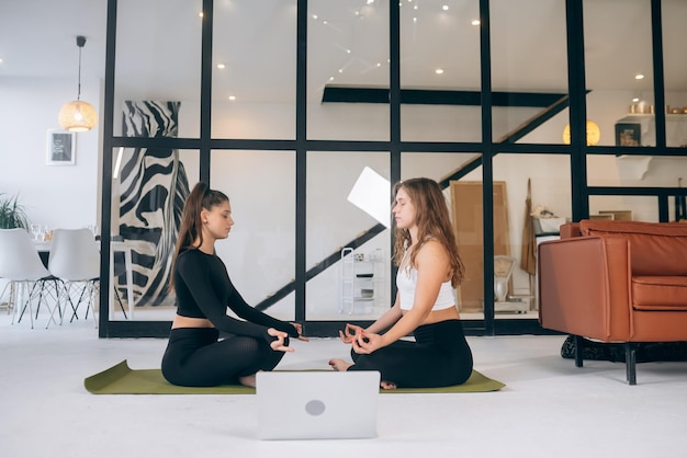 Zwei junge Frauen meditieren zu Hause in Lotus-Pose