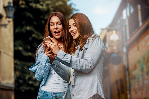 Foto zwei junge frauen mit smartphone auf der straße