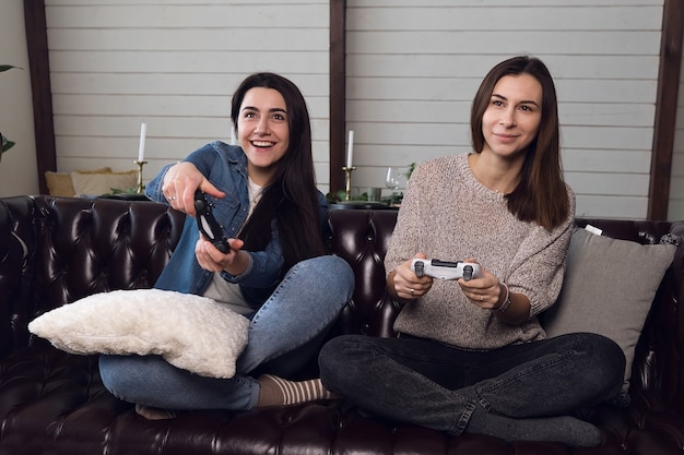 Zwei junge Frauen spielen begeistert Spielkonsole. Hochwertiges Foto