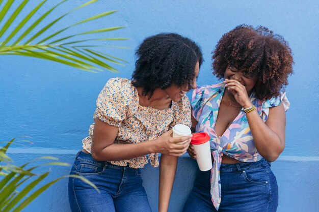 Zwei junge Frauen trinken Kaffee auf der Straße und reden und lachen