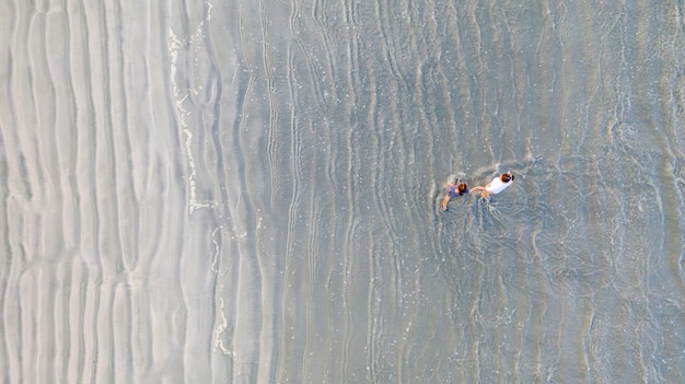 Zwei junge Freunde oder zwei Schwestern, die Hände halten und vorwärts auf den Strand gehen