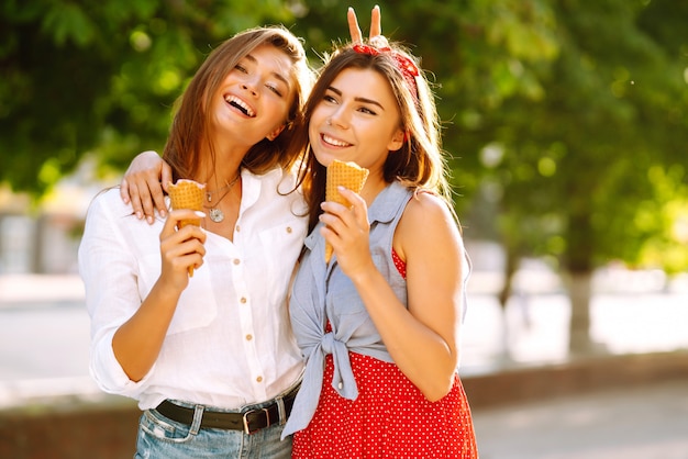 Zwei junge Freundinnen, die Spaß haben und Eis essen.