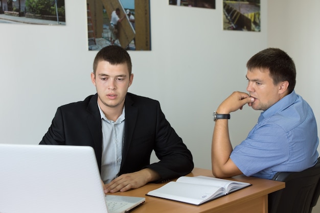 Zwei junge Geschäftsleute, die ernsthaft etwas auf den Computer auf dem Schreibtisch schauen.