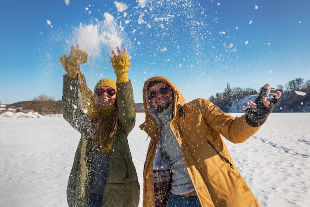 Zwei junge glückliche Menschen, die Schnee werfen und Spaß haben Selektiver Fokus sonniger Wintertag