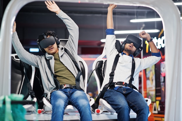 Zwei junge Inder, die Spaß mit einer neuen Technologie eines VR-Headsets am Virtual-Reality-Simulator haben