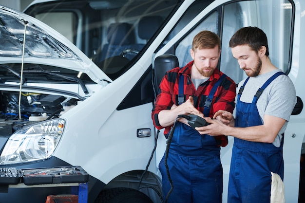 Zwei junge Ingenieure des Pflege-Reparatur-Service-Centers diskutieren Daten in elektronischen Geräten bei der Arbeit