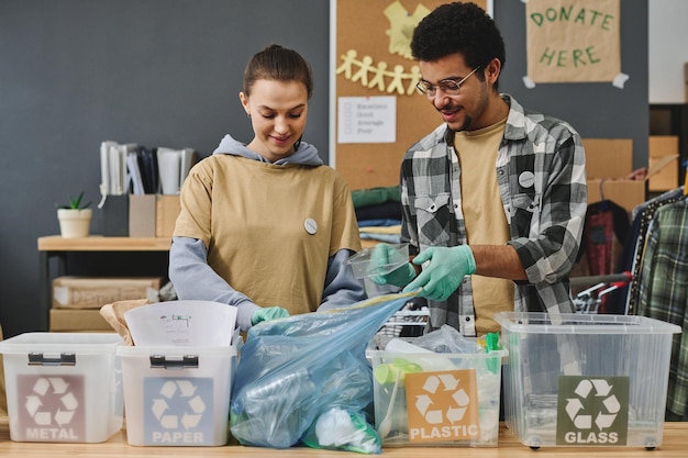 Zwei junge interkulturelle Freiwillige sortieren verschiedene Arten von Müll in Mülleimern