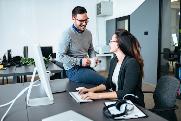 Zwei junge Kollegen, die im modernen Büro sprechen.