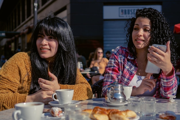 Zwei junge lateinamerikanische Frauen in einer Cafeteria im Freien