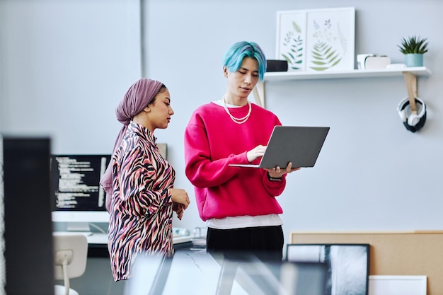 Zwei junge Leute der Generation Z mit Laptop-Weiß stehen im Büro