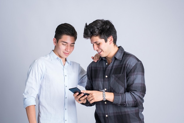 Zwei junge Leute lachen, schauen auf das Telefon und teilen Inhalte in sozialen Netzwerken