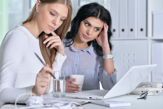 Zwei junge Mädchen, die im Büro mit Laptop arbeiten