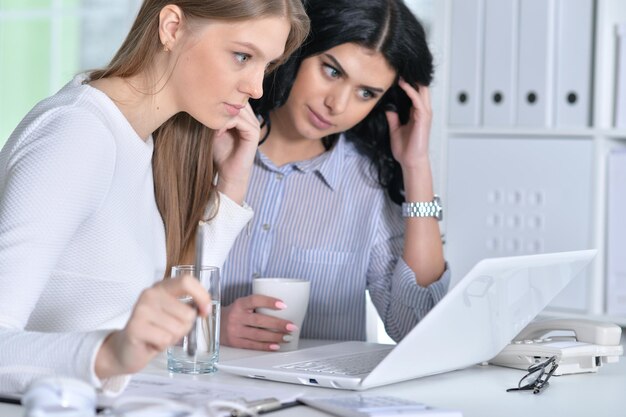 Zwei junge Mädchen, die im Büro mit Laptop arbeiten