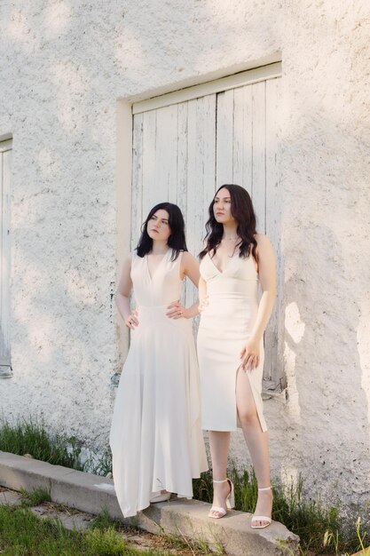 Zwei junge Mädchen im weißen Kleid auf alter weißer Wand des Hintergrundes