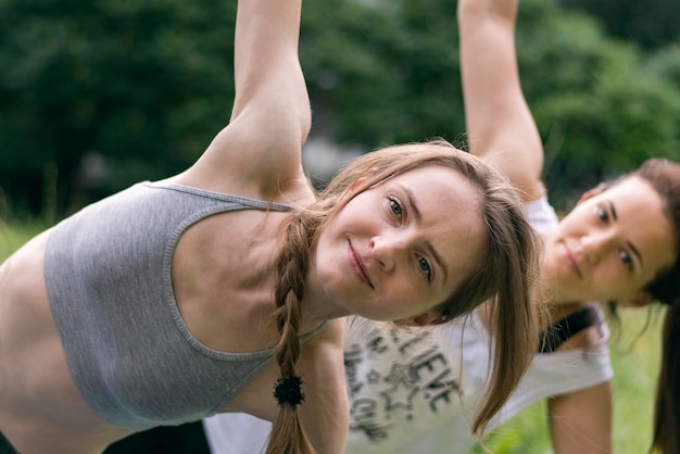 Zwei junge Mädchen machen leichte Übungen im Park Outdoor-Gruppenfitnesskurse Vorderansicht