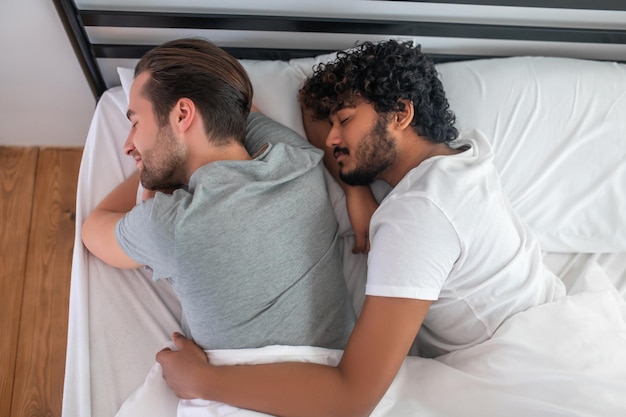 Foto zwei junge männer schlafen im bett und sehen entspannt aus