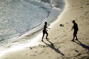 Foto zwei junge männer spielen strandfußball am strand