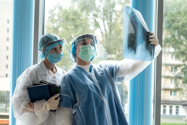 Zwei junge Ärzte, die im Krankenhaus nach einem Röntgenbild der Lunge suchen. Verdacht auf Lungenentzündung