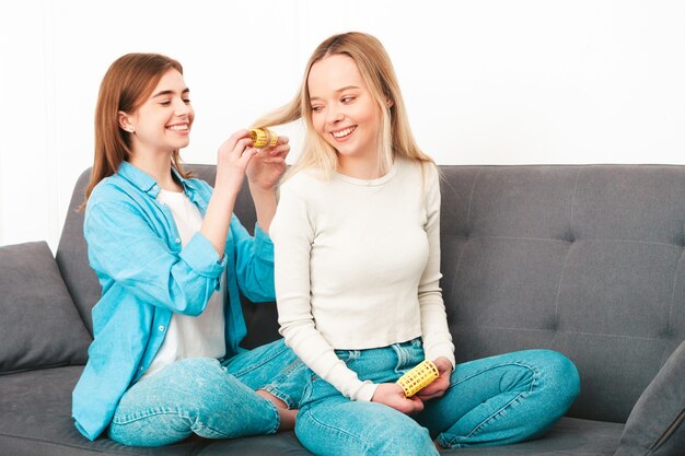 Zwei junge schöne lächelnde Frauen sitzen am Sofa