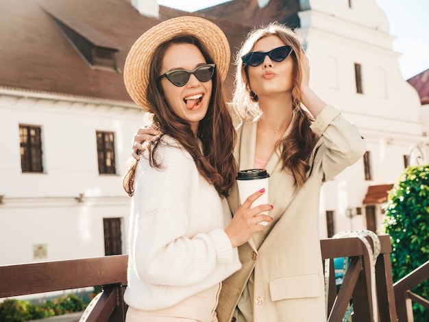 Zwei junge schöne lächelnde Hipster-Frau im trendigen weißen Pullover und Mantel