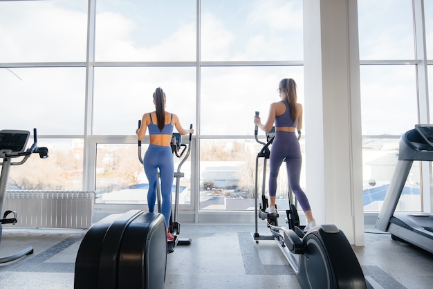 Zwei junge schöne Mädchen trainieren im Fitnessstudio mit Masken während der Pandemie