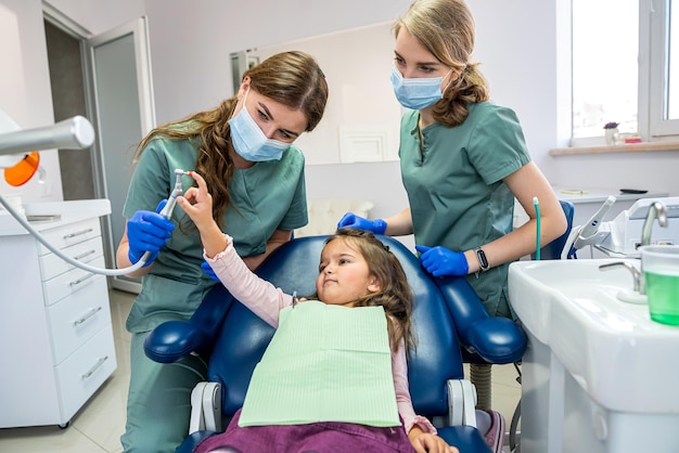 zwei junge schöne zahnärzte in masken und handschuhen reinigen den mund des babys. Konzept zum Zähneputzen von Babys.