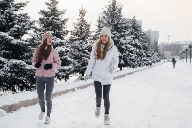 Zwei junge sportliche Mädchen, die an einem sonnigen Wintertag gehen und Sport treiben. Eine gesunde Lebensweise.