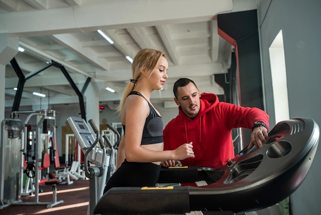 Zwei junge Trainer, ein Mann und eine Frau, trainieren im Fitnessstudio, um die Gesundheit ihres Körpers zu erhalten. Konzept der Trainer im Fitnessstudio