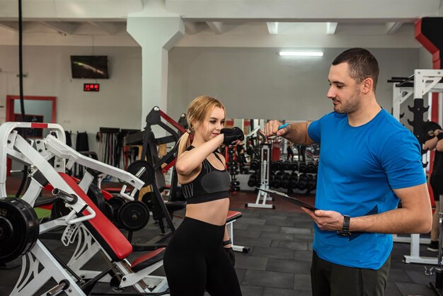 Zwei junge Trainer, ein Mann und eine Frau, trainieren im Fitnessstudio, um die Gesundheit ihres Körpers zu erhalten Konzept der Trainer im Fitnessstudio