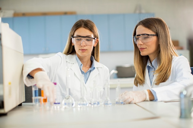 Zwei junge wissenschaftliche Forscherinnen, die eine Flasche mit Lösungen in einem Labor betrachten