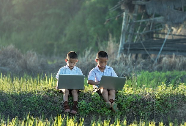 Zwei Jungen, die draußen einen Laptop verwenden