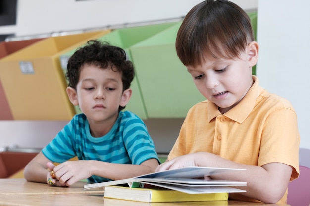 Zwei Jungen, die ein Buch in ihrem Klassenzimmer studieren und lesen