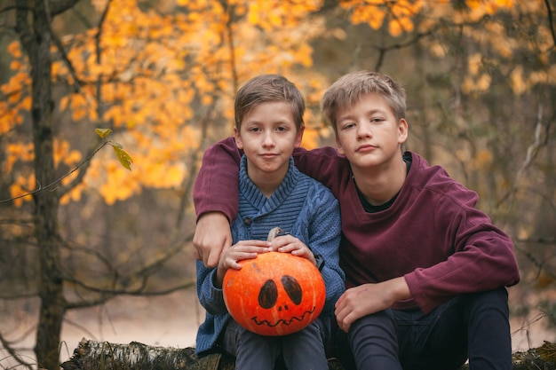 Zwei Jungen, die einen Kürbis halten. Das Konzept der Ferien. Vorbereitung auf Halloween. Ernte.