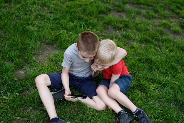 Zwei Jungen mit einem Smartphone im Gras