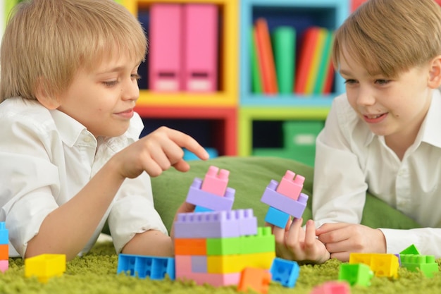 Zwei Jungen spielen mit bunten Plastikblöcken auf dem Boden