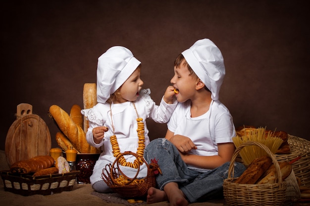 Zwei Jungen und ein Mädchen ziehen sich Plätzchen mit dem Vergnügen ein, das beim Spielen des Chefs aufwirft