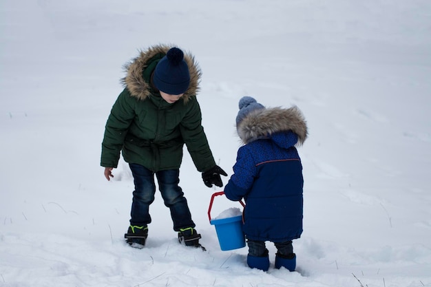 Zwei Jungs spielen im Winter auf Schnee.