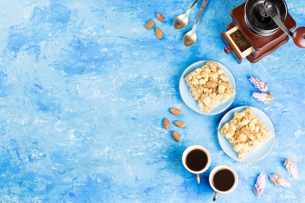 Zwei Kaffeetassen, Kaffeemühle und Apfelkuchen auf blauem künstlerischem. Draufsicht