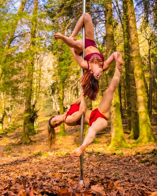 Zwei kaukasische Akrobaten tanzen Pole Dance im Wald im Herbst