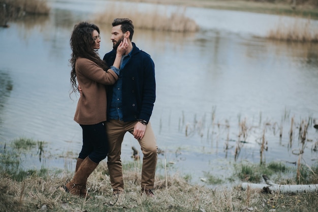 Foto zwei kaukasische liebhaber nahe dem see. ein bärtiger mann und eine verliebte lockige frau. valentinstag.