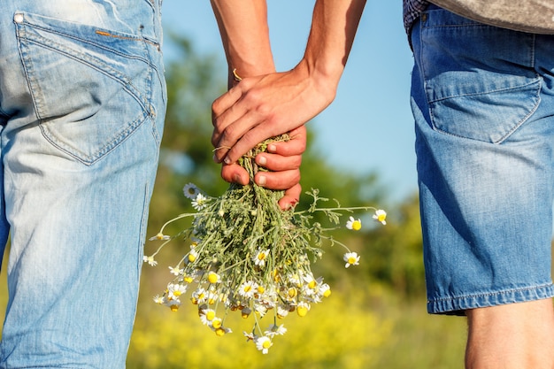 zwei Kerle Händchen haltend mit einem Blumenstrauß des Blumen-Beziehungskonzeptes