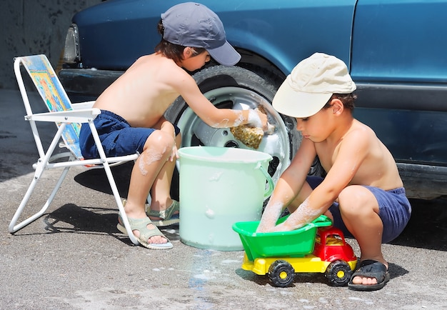 Zwei Kinder, die Auto und Spielzeugauto besiegen