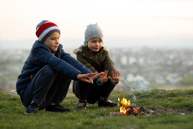 Zwei Kinder, die im Freien bei kaltem Wetter mit Feuer spielen.