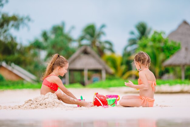 Zwei Kinder, die Sandburg machen und Spaß am tropischen Strand haben