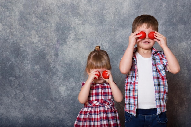 Zwei Kinder, ein Mädchen und ein Junge, halten rote hölzerne Ostereier in ihren Händen