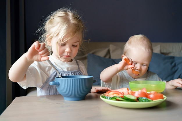 Zwei Kinder essen zu Hause Suppe und Gemüse zum Mittagessen
